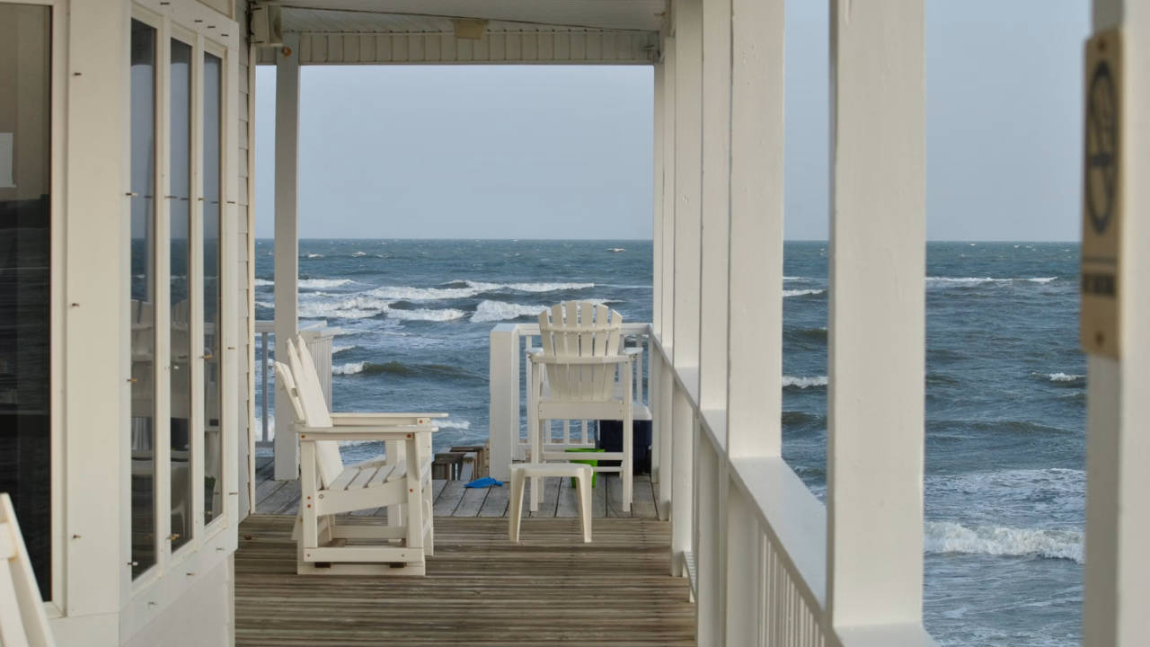 Beach-House-Porch-with-White-Chairs Beach House Porch with White Chairs and Rolling Waves in the Background